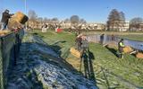 Vrijwilligers plaatsen dranghekken en leggen strobalen langs de ijsbaan in Burgum voor de eerste marathon op natuurijs.