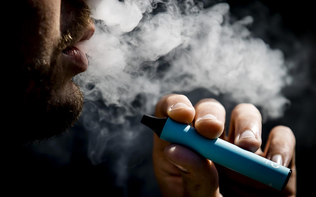 Een jonge man rookt een vaper, oftewel een e-sigaret.